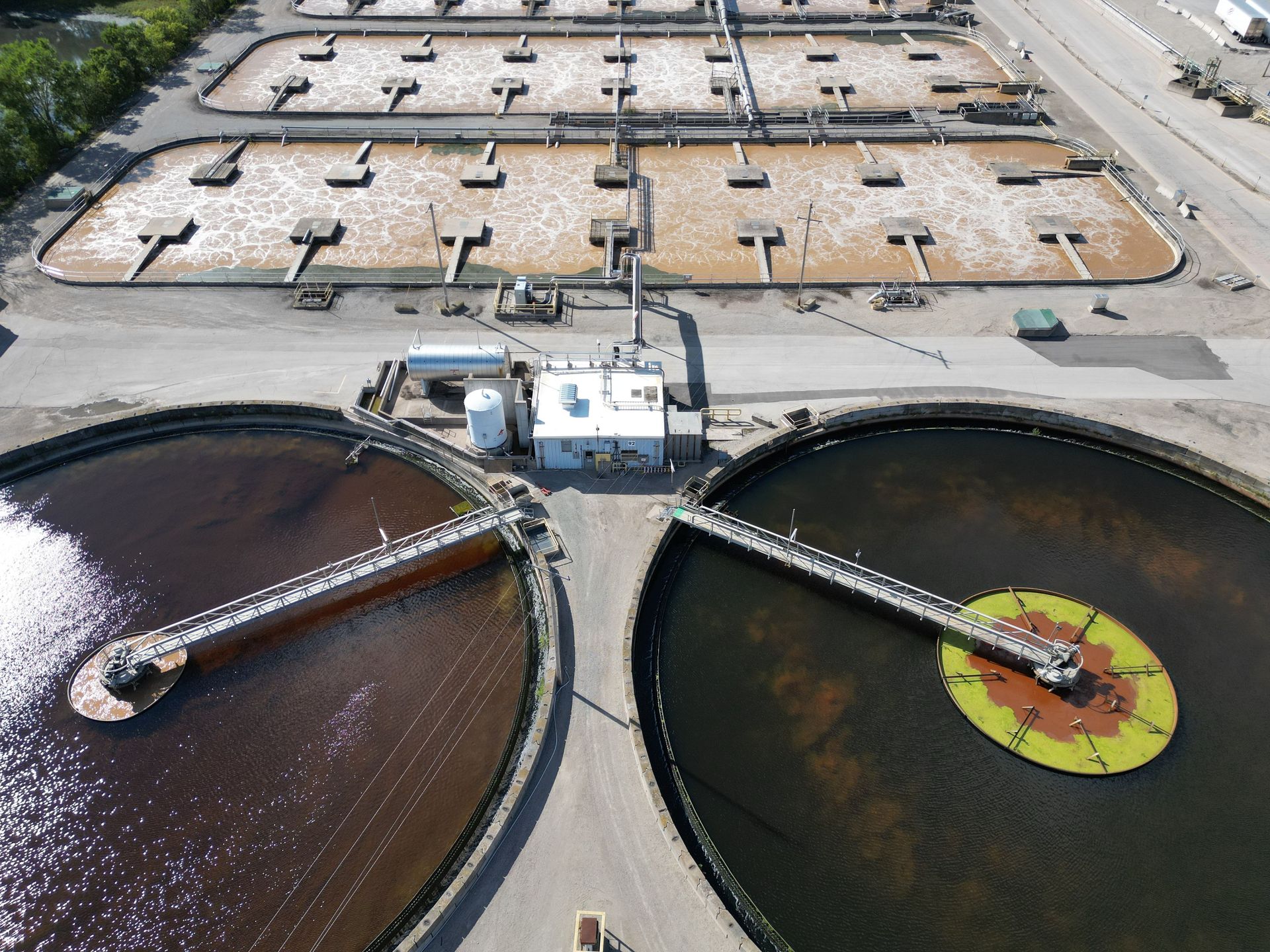 Aerial shot of an industrial water treatment plant with large circular tanks.